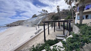 Ein Strandhotel mit Sandstrand, einer überdachten Sitzgelegenheit und Blick auf das Meer.