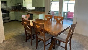 Ett kök med en matplats, inrett med ett träbord och stolar, en inbyggd ugn och en hängande lampa.