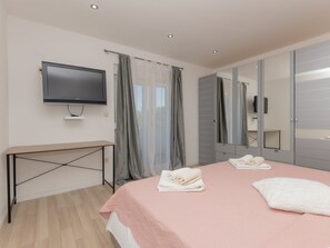 A modern bedroom with a bed, a TV, a desk, and a large mirror.