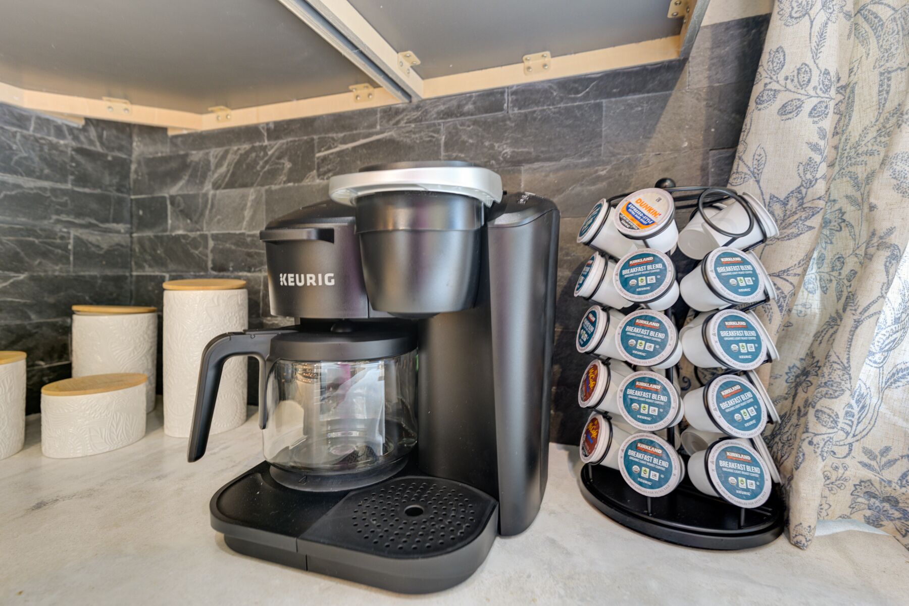 Eine Kaffeemaschine von Keurig mit einem Vorratshalter für Kaffeekapseln, gefüllt mit mehreren Kapseln der Marke Keurig.