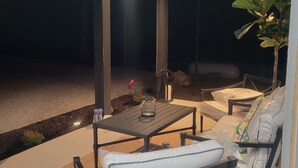 Un espace extérieur aménagé en patio, avec une table et des chaises, une lanterne et une plante en pot.