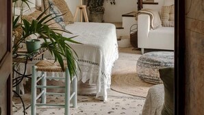 Un dormitorio acogedor con una cama, una silla, una planta y una escalera.