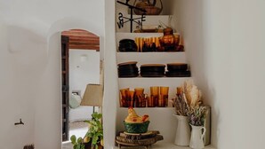 Una cocina con estantes que contienen varios platos y un letrero decorativo con forma de gallo.