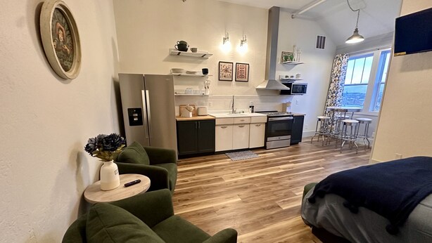 Un espace de vie compact comprenant un coin cuisine, un coin repas et un espace détente avec un canapé et une petite table ronde.