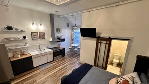 Une chambre moderne équipée d’un lit, d’une petite kitchenette, d’une télévision et offrant une vue sur la ville par une fenêtre.
