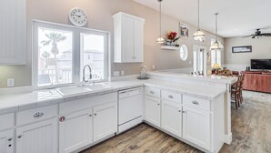 A modern kitchen with white cabinetry, a built-in dishwasher, and a large window.