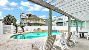 A pool area with lounge chairs and a wooden pergola.