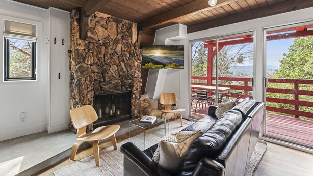 Un salon chaleureux avec une cheminée en pierre, des fauteuils confortables et un grand téléviseur.