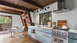Une cuisine moderne avec des poutres en bois, une grande fenêtre et un poêle.