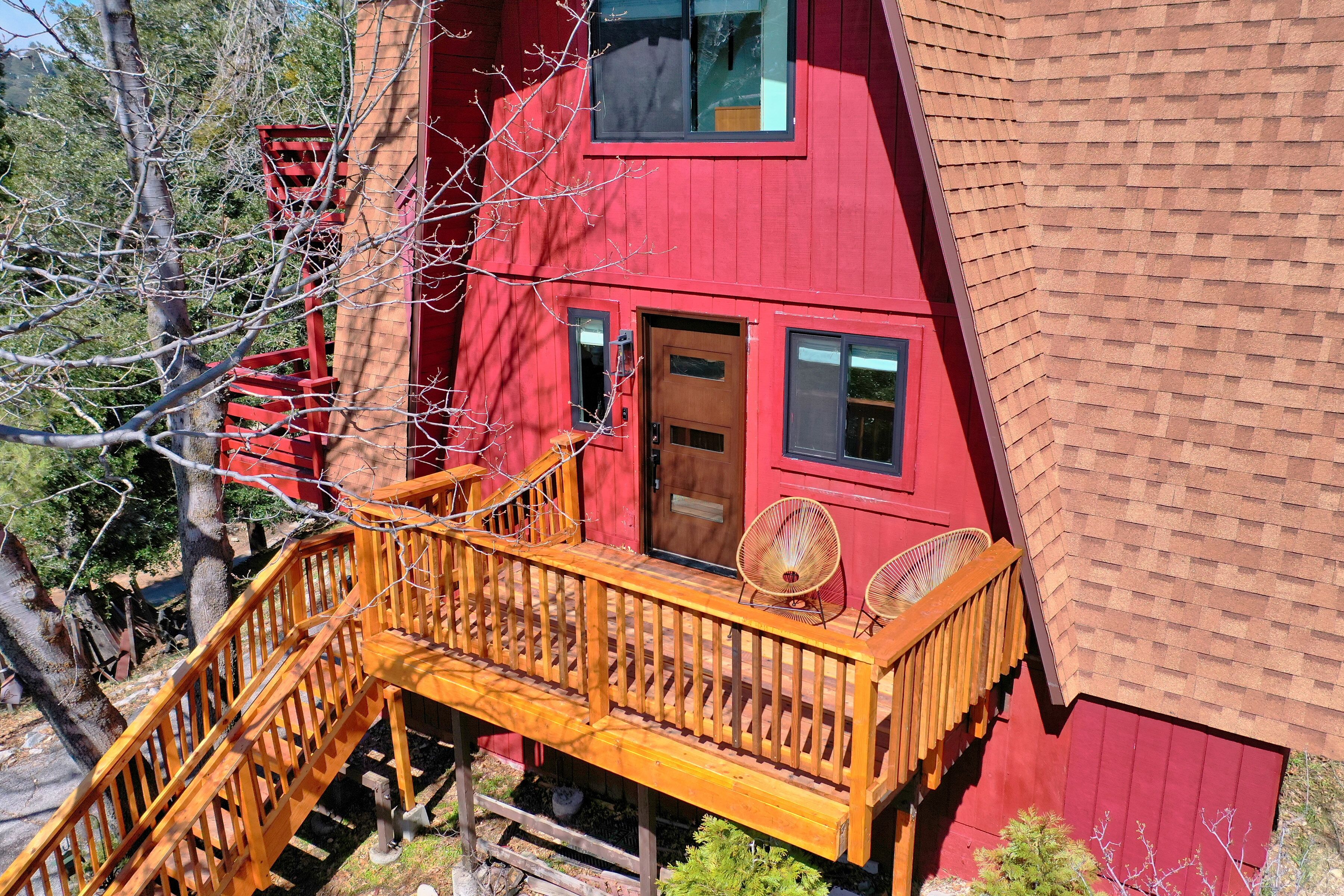 Een rood gebouw met een houten terras en twee stoelen.