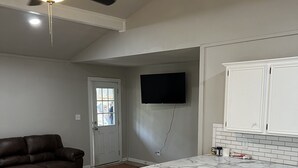 Una cocina con gabinetes blancos, encimera de mármol y ventilador de techo.