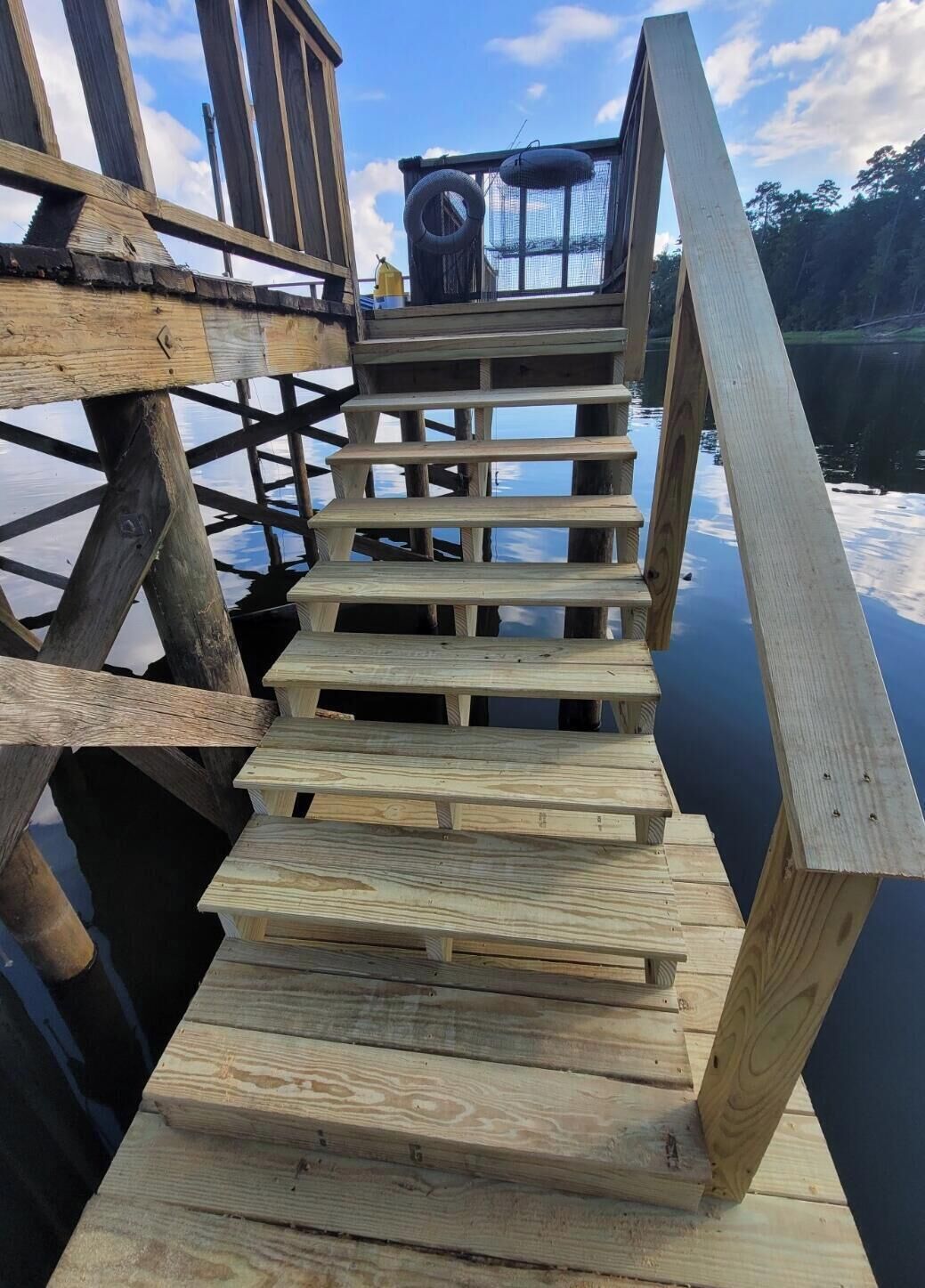 A wooden staircase leading to a platform with a netted enclosure at the top.