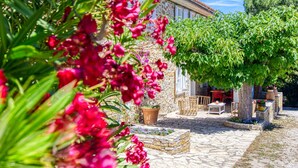 Ein Steinhof mit einer Pergola, Gartenmöbeln und Topfpflanzen.
