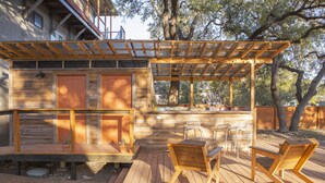 A wooden deck with a pergola, outdoor seating, and a bar area. - The Macaw Yurt at Camposanto ATX Glamping on Lake Travis (Lakeway)