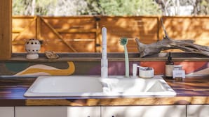 A kitchen with a wooden ceiling, a sink, and a window overlooking trees. - The Macaw Yurt at Camposanto ATX Glamping on Lake Travis (Lakeway)