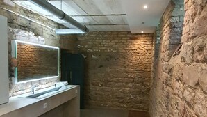 Un pasillo estrecho con una pared de piedra a un lado y una pequeña cocina moderna al otro.