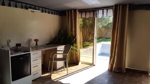A compact kitchen with a dining area, a refrigerator, and a window with curtains. - The Farm Lodge & Spa (Marrakech)