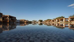 A pool area with a tiled floor and wooden structures on either side, reflecting in the water. - The Farm Lodge & Spa (Marrakech)