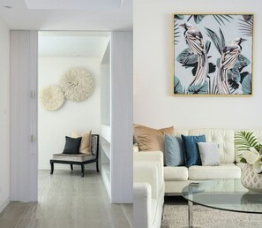 A modern living room with a sofa, a glass coffee table, and a painting of birds on the wall. - Vue One Nelson Bay Waterfront Luxury (Nelson Bay)