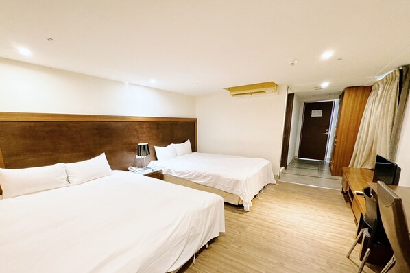 A hotel room with two single beds, a wooden headboard, a desk with a chair, and a door leading to a hallway. - Yoai Nemuru Inn (Tainan)