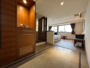 A hotel room with a wooden wardrobe, a bed, a desk, and a large window. - Yoai Nemuru Inn (Tainan)