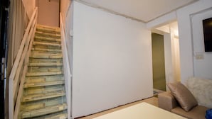A staircase with wooden steps leading to a landing, a white wall, and a sofa with a cushion. - Treasure Isle Backpacker's Hostel (Boracay Island)