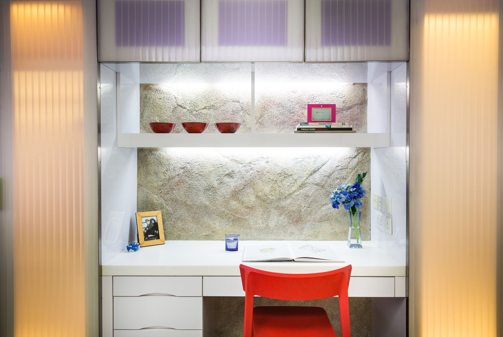 Une cuisine moderne avec des armoires blanches, un comptoir en granit et une chaise rouge.