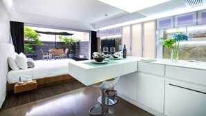 A modern hotel room with a bed, a dining area with a white table, and a view of the outdoors. - V Wanchai (Hong Kong)