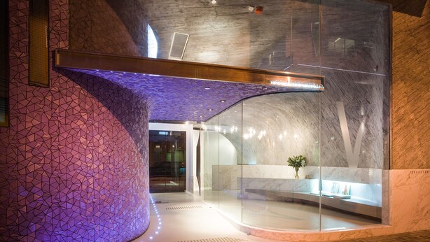 A modern interior with a curved wall, a glass display case, and a patterned ceiling. - V Wanchai (Hong Kong)