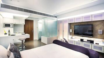 Et moderne hotelværelse med en stor seng, et fjernsyn, minibar og et separat spiseområde.