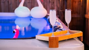 Et poolområde med to svaneudsmykninger og to champagneglas på en træbakke.