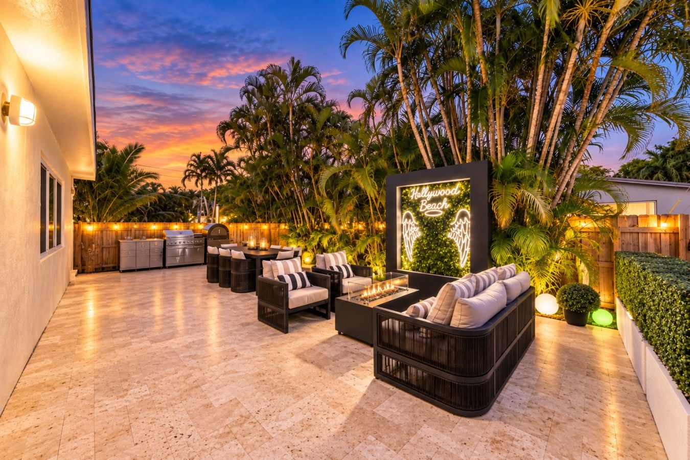 An outdoor patio with seating, a grill, and a neon sign.