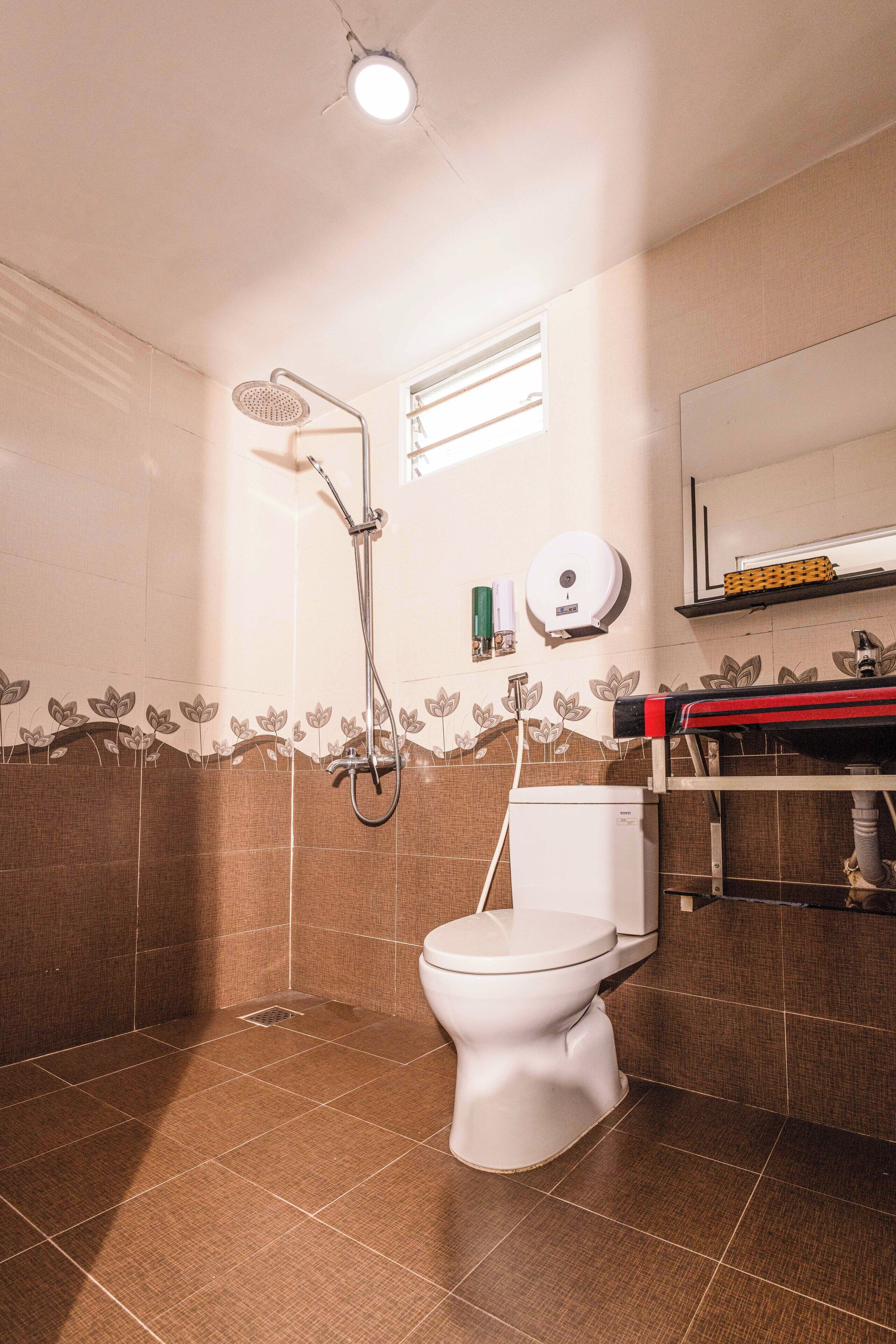 A bathroom with a shower, toilet, and a mirror.