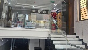 A modern interior with a glass staircase, a chandelier, and a visible store named "EN PHU". - Uyên Phương Hotel Nha Trang (Nam Nha Trang)