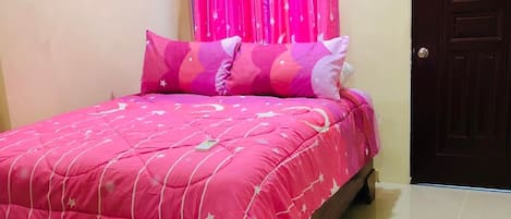 A bedroom with a bed covered in pink bedding, a wooden door, and a tiled floor.