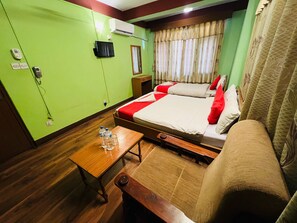 A hotel room with a bed, bedside table, and a small wooden bench. - Hotel Green Orchid pvt ltd (Kathmandu)
