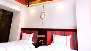 Een hotelkamer met een groot bed, een plafondventilator en een kroonluchter.