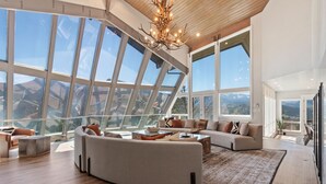 Un salón espacioso con un sofá seccional grande, una mesa de centro y vistas al exterior a través de amplias ventanas.