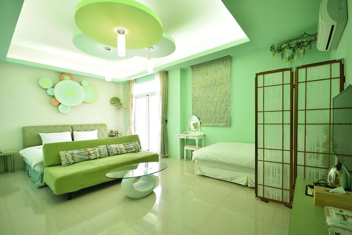 Quarto moderno com sofá verde, mesa de centro redonda de vidro, cama e um painel deslizante shoji.