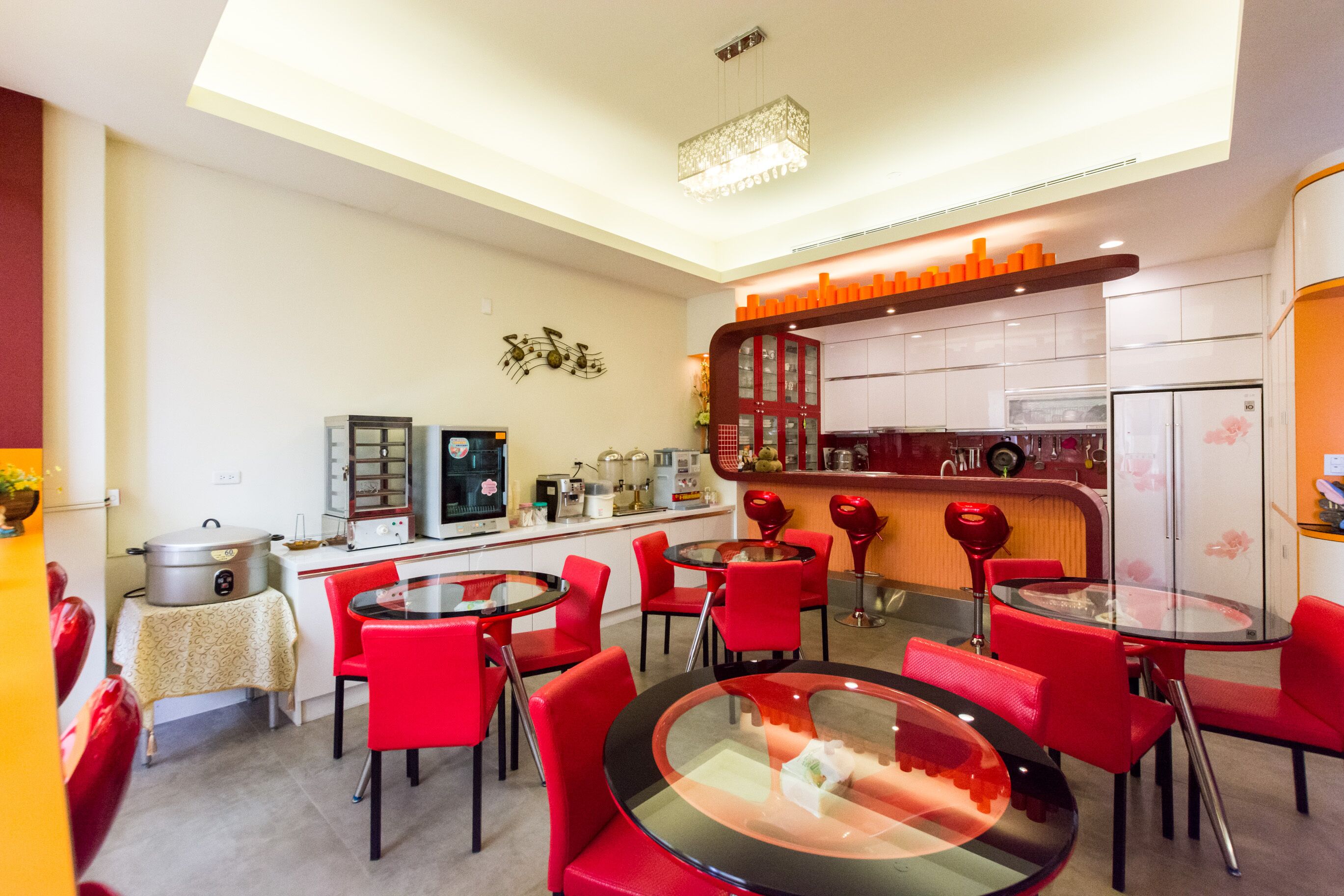 Une cuisine moderne avec des chaises rouges, une table en verre et un coin bar.