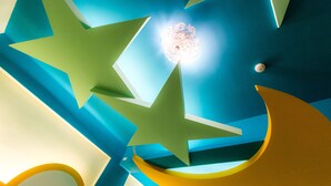 Een plafond met geometrische vormen en een bolvormige lamp.