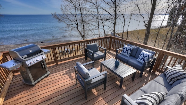 A deck with a grill, seating, and a view of the lake. - Sisu Shores: Lakefront Home with Private Beach and Wood Burning Sauna (Duluth)