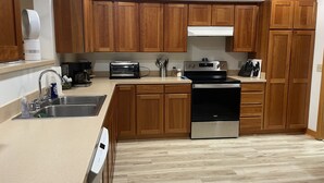 A modern kitchen with wooden cabinets, a stainless steel sink, a built-in oven, and a toaster.