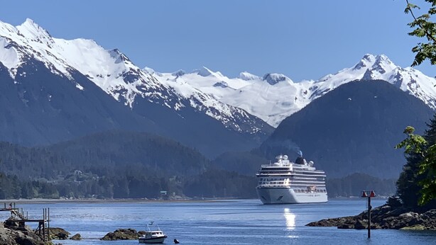 A cruise ship on a calm lake with snow-capped mountains in the background.