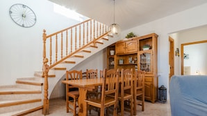 Eine Treppe mit Holzgeländern führt zu einem Essbereich mit Holztisch und Stühlen.