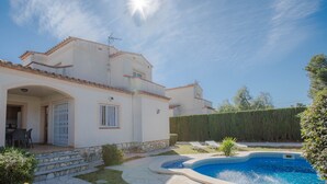 Ein zweistöckiges Haus mit Swimmingpool, Steinstufen und einer überdachten Terrasse.
