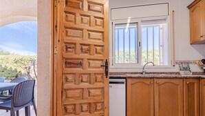 Eine Küche mit Holzausstattung, einem Geschirrspüler und einem Fenster mit Jalousien.