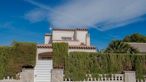Una casa de dos pisos con techo de tejas, una chimenea y un portón.