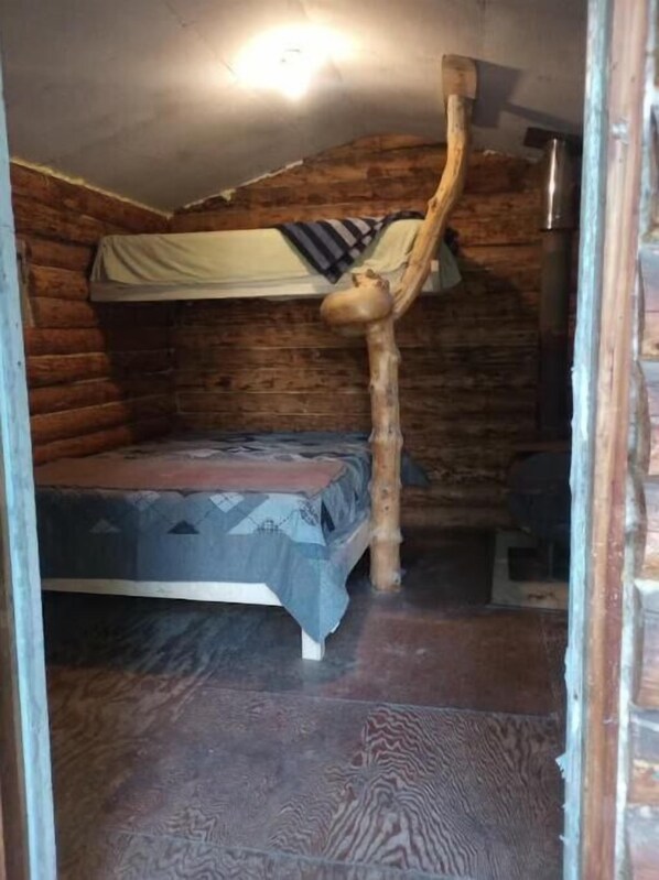 Une chambre aménagée dans un chalet en rondins, avec un lit superposé, une chaise en bois et une petite table.