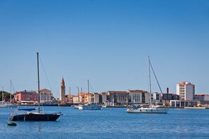 A marina with boats, a clock tower, and buildings with red roofs. - Apartment Ayni With Private Pool (Umag)